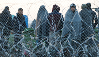 Migrants stand behind a border fence imposed by Macedonian authorities at the Greek-Macedonian border, near the village of Idomeni (Reuters/Marko Djurica))