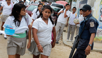 School girls walk past a policeman in Acapulco (Reuters/Tomas Bravo)