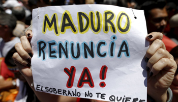 An opposition supporter holds a sign that reads, "Maduro resign now. The sovereign does not love you", during a rally in Caracas (Reuters/Carlos Garcia Rawlins)