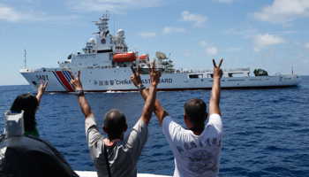 Philippine Marines and a television reporter gesture towards a Chinese Coast Guard vessel (Reuters/Erik De Castro)