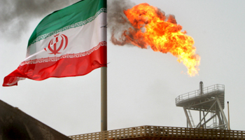 A gas flare on an oil production platform alongside an Iranian flag in the Gulf (Reuters/Raheb Homavandi/File Photo)