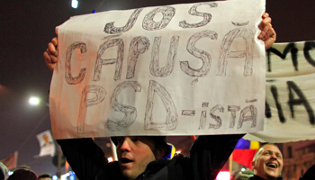 A protester at a rally during the November 2014 presidential election holds a placard reading "Down with the PSD -- tick" (Reuters/Radu Sigheti)