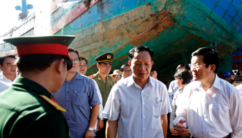 Vietnam’s former President Truong Tan Sang, right, talks to local officers near damaged fishing boat DNA90152, which was rammed and then sunk by Chinese vessels in, 2014 (Reuters/Kham)