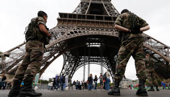 Soldiers stand by tourists as they patrol near the Eiffel Tower in Paris (Reuters/Gonzalo Fuentes)