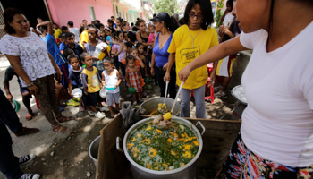 A volunteer distributes free meals among residents in a low-income neighborhood in Venezuela (Reuters/Henry Romero)