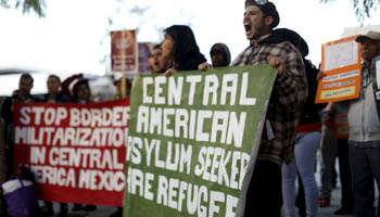 People hold signs as they gather outside a Federal Building while protesting against Immigration and Customs Enforcement (ICE) raids on Central American refugees in Los Angeles, California (Reuters/Mario Anzuoni)