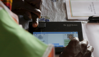 An election official checks biometric identification of a voter in the Ivory Coast  (Reuters/Thierry Gouegnon)