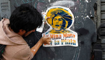 A worker pastes a sticker, which reads, "The mine kills for money," on a wall, in solidarity with the anti-mining protest in Cajamarca, Lima (Reuters/Mariana Bazo)