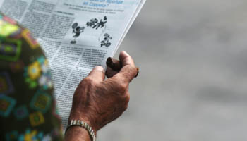 A man smokes a cigar as he reads a local newspaper in Havana, Cuba (Reuters/Alexandre Meneghini)