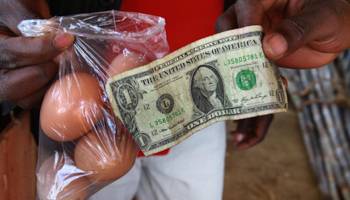 A man buys eggs using a US dollar at a market in Harare, Zimbabwe (Reuters/Philimon Bulawayo)