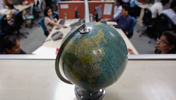Employees work behind a globe (Reuters/Vivek Prakash)