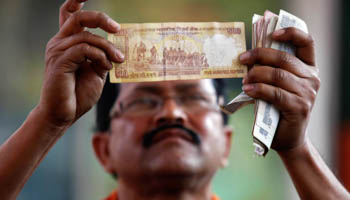 A worker at a fuel station checks a 500 Indian rupee note in Kolkata (Reuters/Rupak De Chowdhuri)