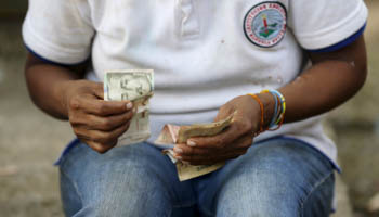 A woman counts money at a park in San Jose del Guaviare (Reuters/John Vizcaino)