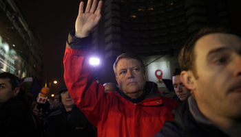 President Klaus Iohannis waves to protesters at a demonstration in Bucharest against government plans to grant prison pardons and decriminalise offences by emergency decree (Reuters)