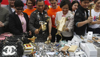 Officials from Thailand's Department of Intellectual Property and police force destroy counterfeit goods in Bangkok, Thailand (Reuters/Chaiwat Subprasom)