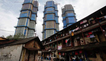 High-rise residential towers under construction contrast a rundown residential building in central Mumbai (Reuters/Vivek Prakash)
