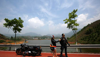 A couple stand next to their motorcycle in Qian Dao Lake, Zhejiang Province (Reuters/Carlos Barria)