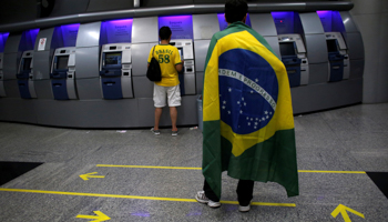 A man wearing a Brazilian flag waits in a Banco do Brasil branch (Reuters/Nacho Doce)