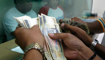 Customers count their peso notes at a money changer in Manila (Reuters/Cheryl Ravelo)