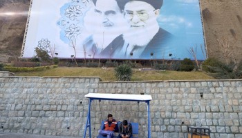 Iranian youths sit under a picture of Iran's late leader Ayatollah Ruhollah Khomeini, left, and Iran's Supreme Leader Ayatollah Ali Khamenei at a park in Tehran (Reuters/Raheb Homavandi)