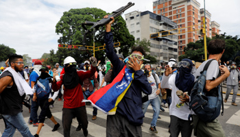 Opposition protesters hold a shotgun taken from riot police, May 3 (Reuters/Carlos Garcia Rawlins)