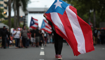 A demonstrator carries a Puerto Rican flag during a May 1 anti-austerity protest in San Juan, Puerto Rico (Reuters/Alvin Baez)