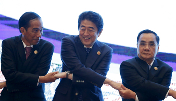 Left to right, Indonesia's President Joko Widodo, Japan's Prime Minister Shinzo Abe and Laos’s then Prime Minister Thongsing Thammavong link hands at the 27th ASEAN summit in Malaysia, 2015  (Reuters/Olivia Harris)