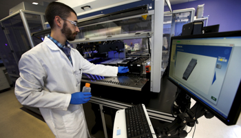 A technician loads a robotic DNA sample automation machine at a the biotechnology company, Regeneron Pharmaceuticals Inc (Reuters/Mike Segar)