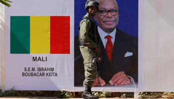 A Malian soldier stands guard next to Malian President Ibrahim Boubacar Keita's portrait, 2017 (Reuters/Luc Gnago)