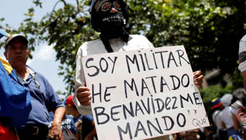 A protester with a sign saying “I am military. I have killed. [National Guard chief] Benavides ordered me.” (Reuters/Marco Bello)