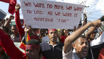 A protester holds a placard outside the Australian Embassy in Dili, March 22, 2016 (Reuters//Lirio da Fonseca)