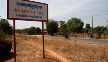 A man rides a motorcycle past a signboard for the Cambodia Iron Group, Rovieng District (Reuters/Samrang Pring)