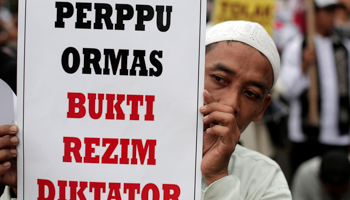 An Islamist Group member protesting against President Joko Widodo's decree to disband certain groups. The placard reads "Regulation for mass organizations is evidence of a dictatorial regime" Jakarta, Indonesia (Reuters/Beawiharta)