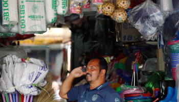 A Burmese migrant worker talks on his cell phone near a wholesale market, in Samut Sakhon province, Thailand (Reuters/Chaiwat Subprasom)