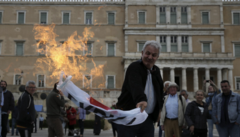 A demonstrator burns the Syriza flag outside parliament as lawmakers vote on the latest round of austerity Greece has agreed with its lenders, Athens (Reuters/Costas Baltas)