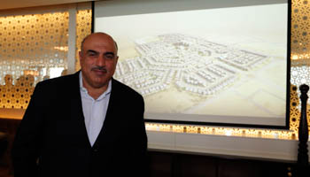 Naseej Chairman Khalid Abdulla-Jahani poses next to a picture of a projected public-private partnership project, Manama (Reuters/Hamad I Mohammed)