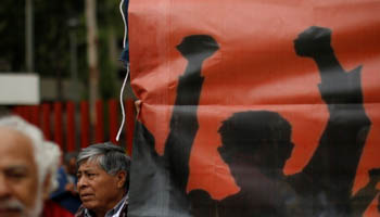 A man stands next to a banner during a union workers' rally as the second round of NAFTA talks involving the United States, Mexico and Canada begins in Mexico City, Mexico September 1, 2017 (Reuters/Carlos Jasso)