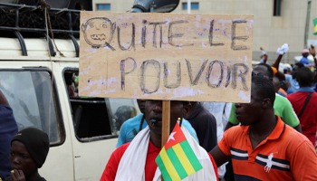 A man holds up a sign which reads "leave the power" during opposition protests in Togo (Reuters/Noel Kokou Tadegnon)
