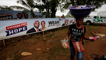 A vendor passes by a poster for presidential candidate Senator George Weah in Monrovia (Reuters/Thierry Gouegnon)