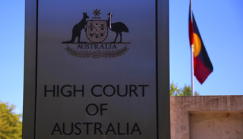 The Australian Aboriginal flag behind a sign for the High Court of Australia building in Canberra (Reuters/David Gray)
