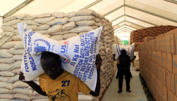 People carry sacks of dry food rations from the World Food Programme store, for distribution to South Sudanese refugees, at the Palabek Refugee Settlement Camp in Lamwo district, Uganda (Reuters/James Akena)