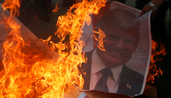 A Palestinian protester burns a poster depicting US President Donald Trump during a protest against Trump's decision to recognize Jerusalem as the capital of Israel, in Gaza City (Reuters/Mohammed Salem)