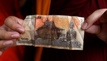 A Buddhist monk holds a riel banknote with the image of Buddha at a store in Phnom Penh, Cambodia (Reuters/Samrang Pring)