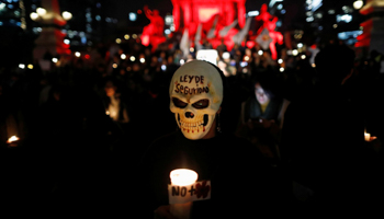 An activist in mask holds a candle during a protest against a new security bill, Law of Internal Security, in Mexico City, December 13, 2017 (Reuters/Edgard Garrido)
