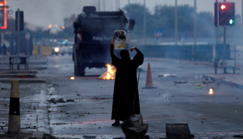 A female protester holds a photo of Shi'ite scholar Isa Qassim as she confronts riot police during a demonstration (Reuters/Hamad I Mohammed)