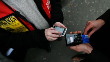 A Big Issue vendor demonstrates using a Chip and Pin device, London, UK (Reuters/Stefan Wermuth)