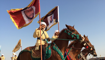 Costumed desert knights with banners depicting Abu Dhabi's ruling sheikhs in Sweihan, UAE (Reuters/Noah Browning)