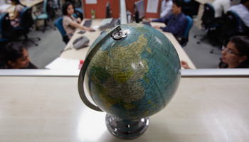Employees work behind a globe on the floor of the outsourcing company WNS in Mumbai (Reuters/Vivek Prakash)