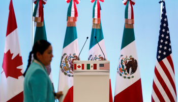 A woman walks by the flags of Canada, Mexico and the United States before a joint news conference on the closing of the seventh round of NAFTA talks in Mexico City, March 5 (Reuters/Edgard Garrido)