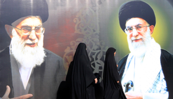 Women walk past a poster depicting images of Iran's Supreme Leader Ayatollah Ali Khamenei (Reuters/Ahmed Saad)